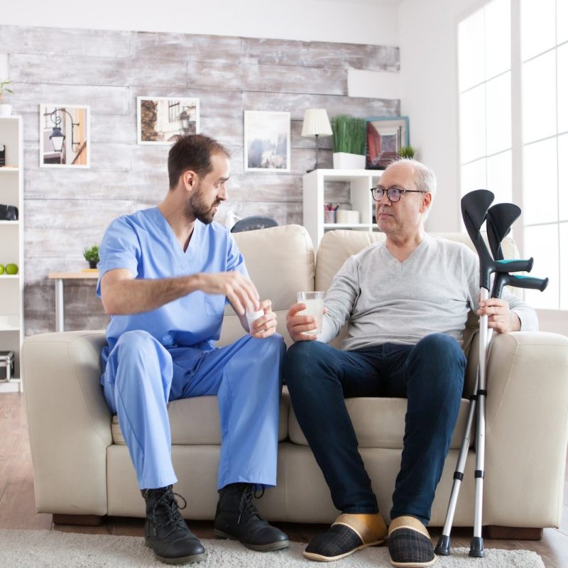 young-male-nurse-in-nursing-home-with-pills-for-senior-man.jpg